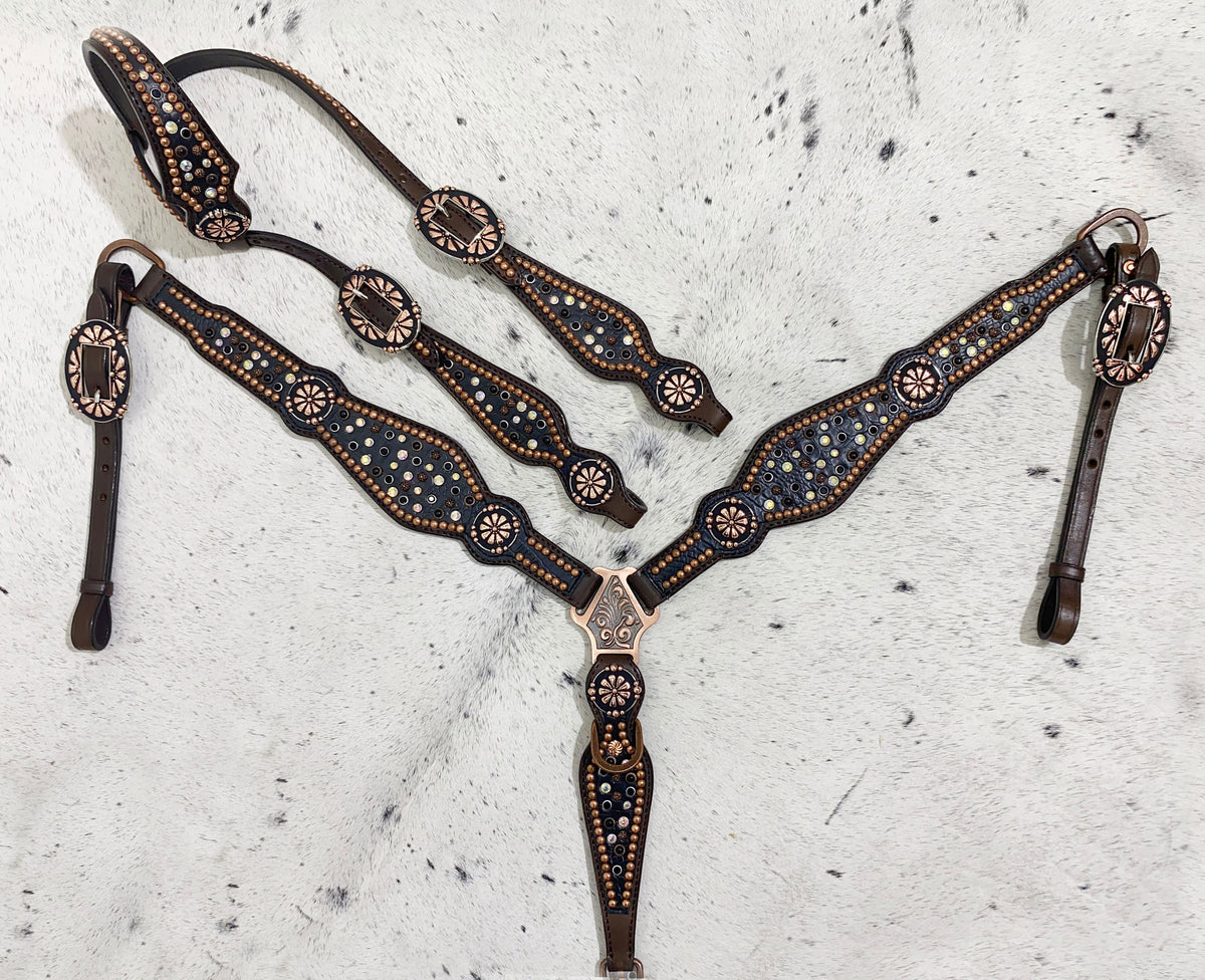 A set of Western horse tack including a headstall and breast collar with black rhinestone accents and copper colored hardware, displayed on a light background.