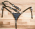 A cow leather headstall and breast collar set with black alligator pattern, clear rivets, and silver studs on a wooden surface.
