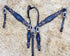 A set of Argentina cow leather Western horse tack, featuring a black alligator print with topaz rhinestone accents and copper studs, laid out on a bed of straw.
