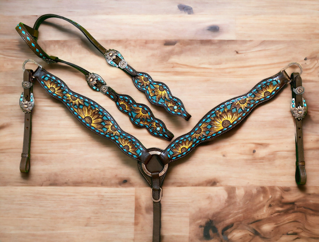 A set of Argentina cow leather horse tack including a headstall and breast collar with hand-painted sunflower carving and teal rawhide stitching, laid out on a wooden surface.