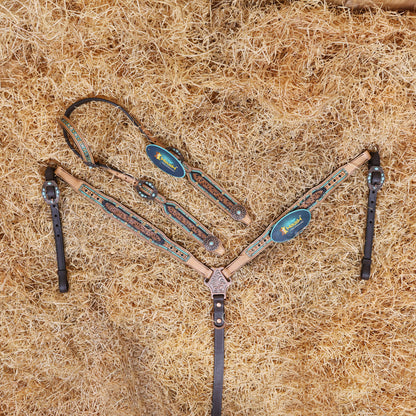A tooled leather Western headstall and breast collar set with floral design, featuring topaz and black rivets, and antique copper hardware, laid out on a bed of straw.