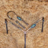 A tooled leather Western headstall and breast collar set with floral design, featuring topaz and black rivets, and antique copper hardware, laid out on a bed of straw.