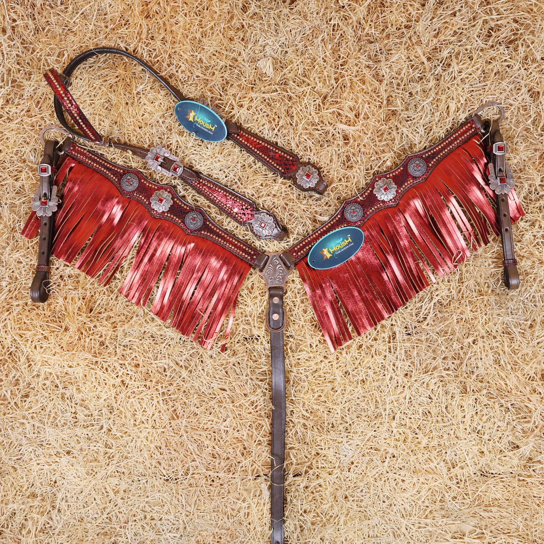 Argentina Cow Leather headstall and breast collar set with red metallic snake print and fringe, featuring antique brass hardware, displayed on a bed of straw.